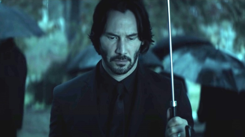 John Wick holding umbrella and looking down