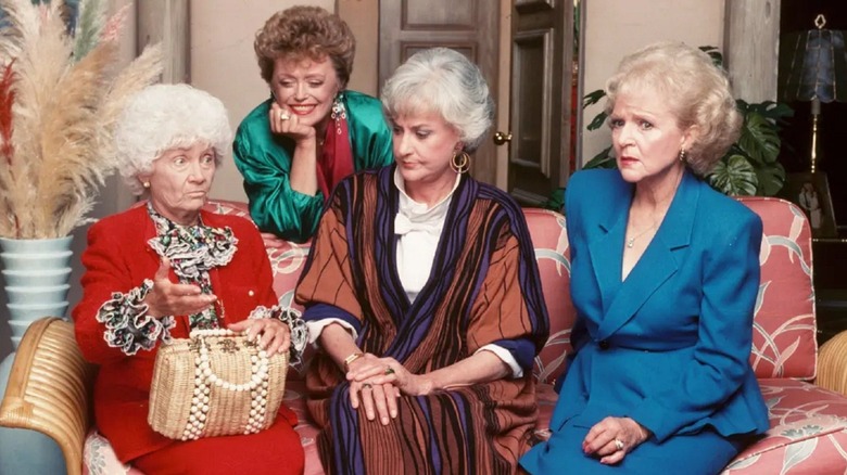 Sophia, Blanche, Dorothy, and Rose sitting together on the couch in "The Golden Girls"