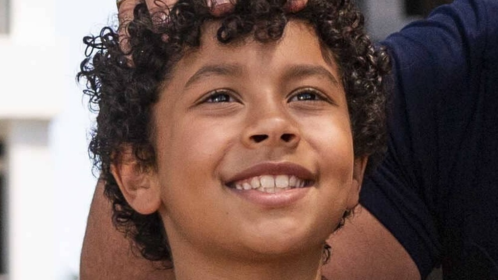 Young Rock on a swing hand on his head