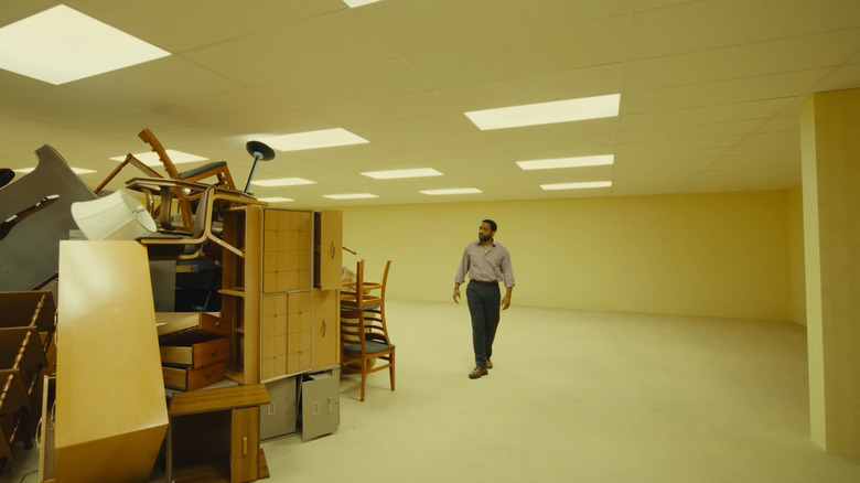 Clark looking at a mess of furniture in Backrooms