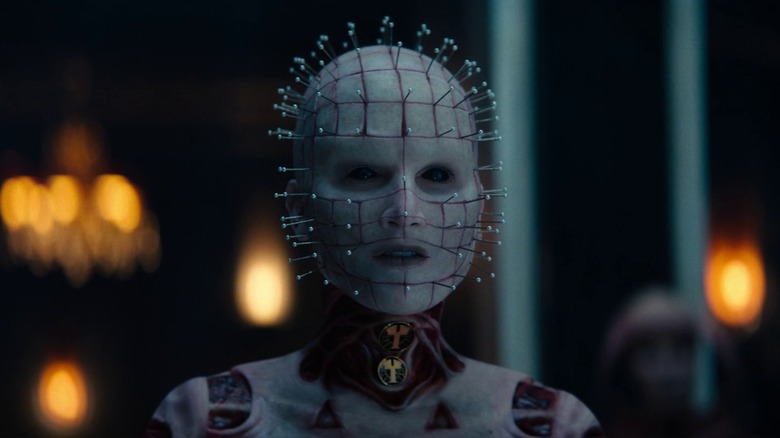 The genderfluid Hellpriest of Hellraiser (2022), lit by candles from behind