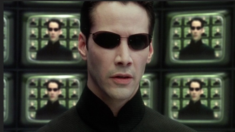 Neo surrounded by screens showing his own face in 