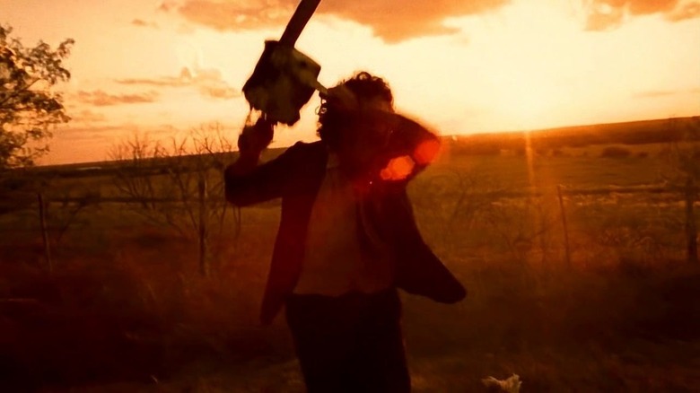 Leatherface wielding his chainsaw outside at sunrise in "The Texas Chainsaw Massacre."