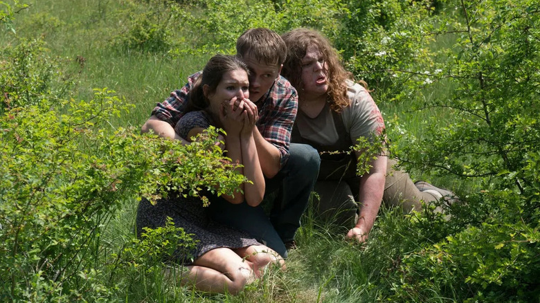 Three people hiding in grass in "Leatherface."
