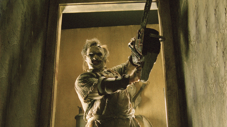 Leatherface standing in a doorway with a chainsaw in "The Texas Chainsaw Massacre."