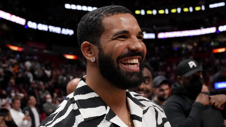 Drake smiling in basketball arena