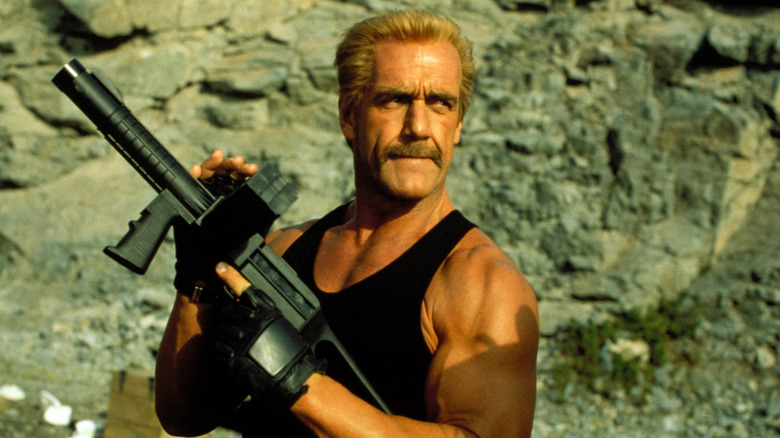 Cutter stands on a rockface holding a machine gun in Ultimate Weapon