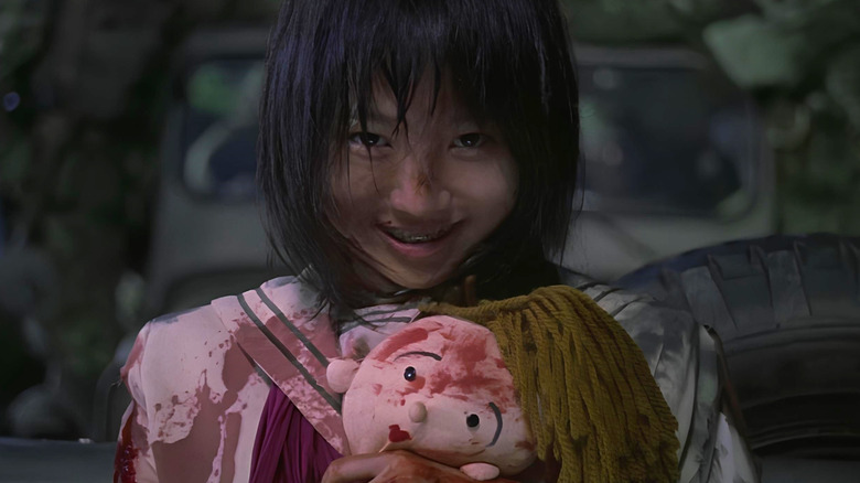 Mai clutches a blood-stained doll