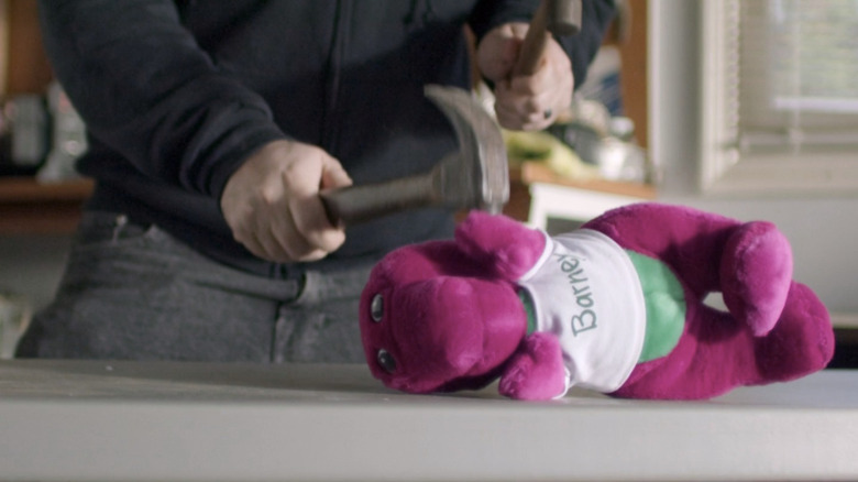 Person hitting a Barney plush