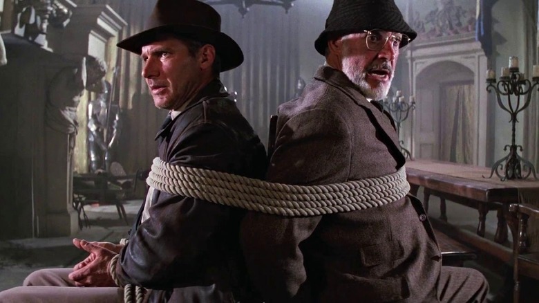 Indiana and Henry Jones sit behind each other while being tied up in Indiana Jones and the Last Crusade (1989)