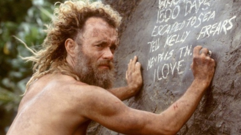 Chuck Noland writing a note on rock