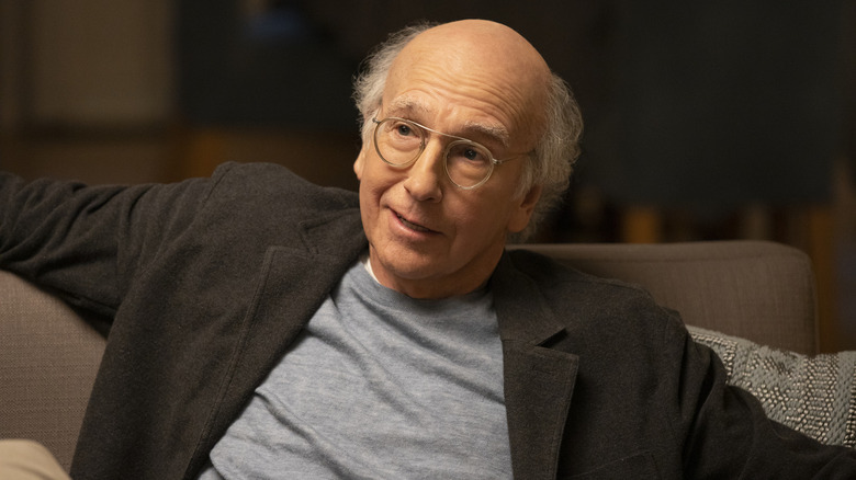 Larry David smiling on sofa