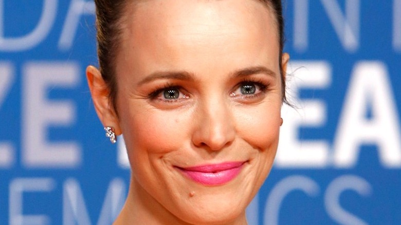 Rachel McAdams smiles in front of a blue and white background