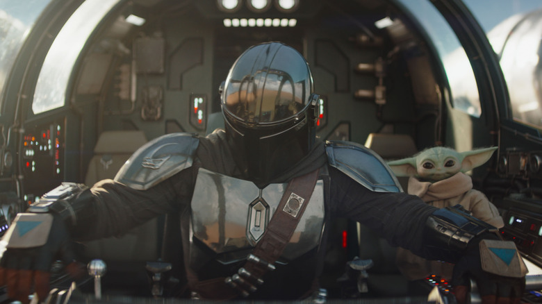 Din Djarin piloting a starfighter with Grogu in the passenger seat in The Mandalorian and Grogu