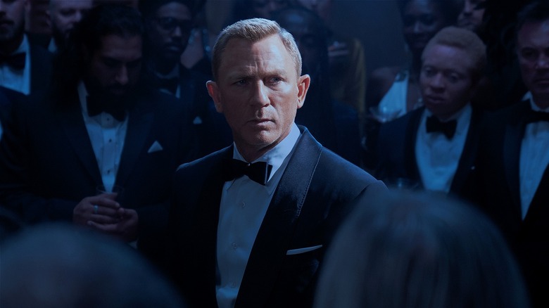 Bond standing in crowd of men in tuxes (2021)