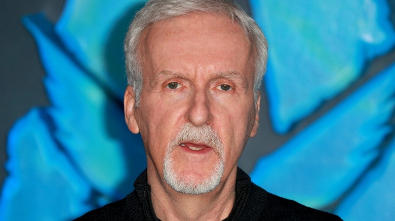 James Cameron standing in front of Avatar logo