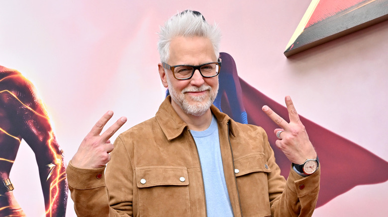 James Gunn posing with peace signs on red carpet 