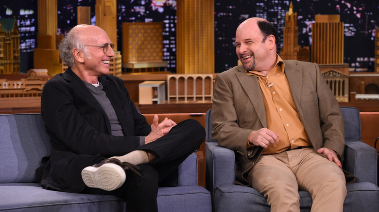 Larry David and Jason Alexander sitting on couch
