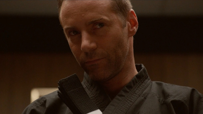 Sensei holding a black belt inside his Gi in "The Art of Self-Defense" (2019)