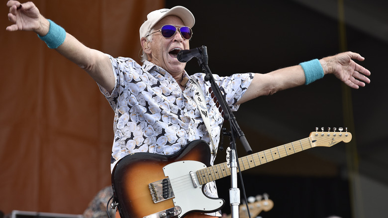 Jimmy Buffett performing onstage with a guitar
