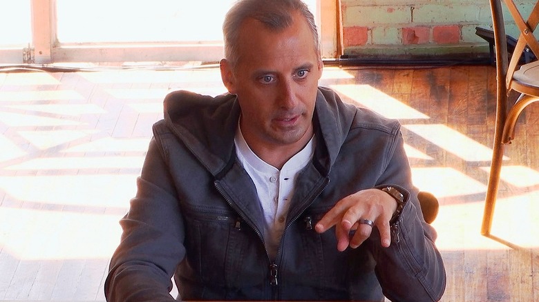 Joe Gatto holding a phone with his hand outstretched 