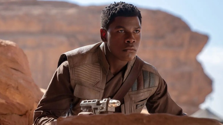 Finn peering over rock holding gun