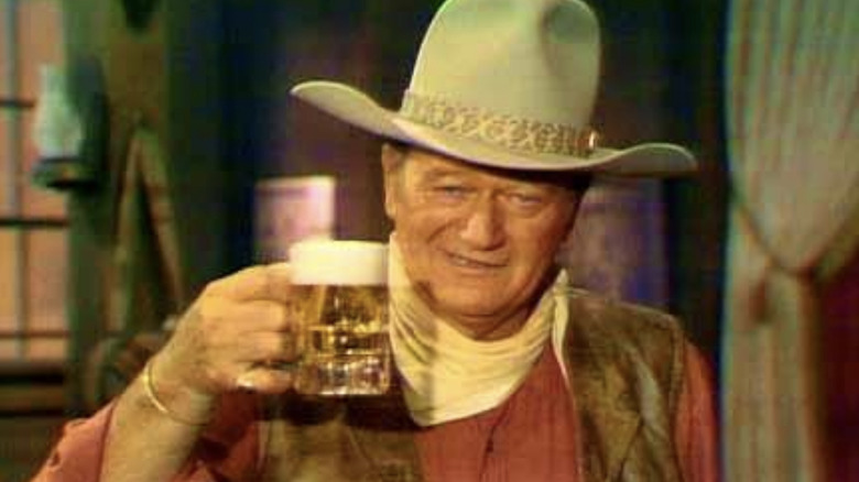 John Wayne in Rio Bravo-inspired apparel with a Budweiser beer in Swing Out, Sweet Land (1970)