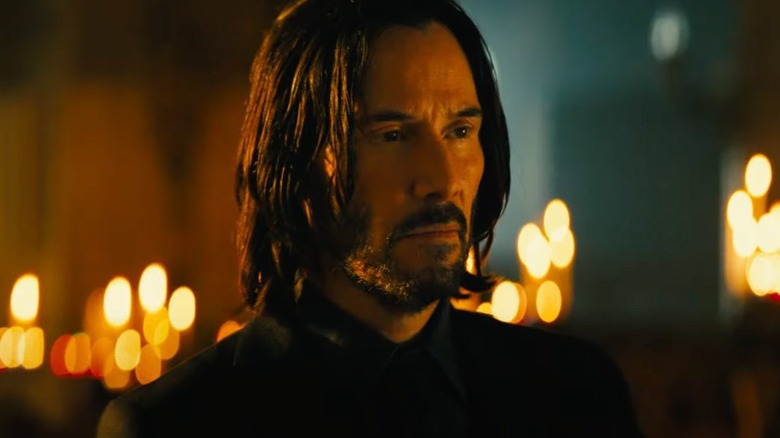 John Wick standing in front of candles