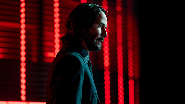 John Wick standing red lights behind