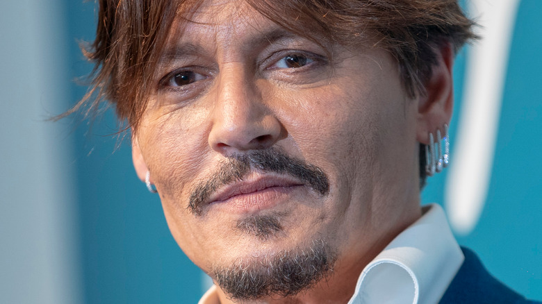 Johnny Depp smiling in front of a blue backdrop