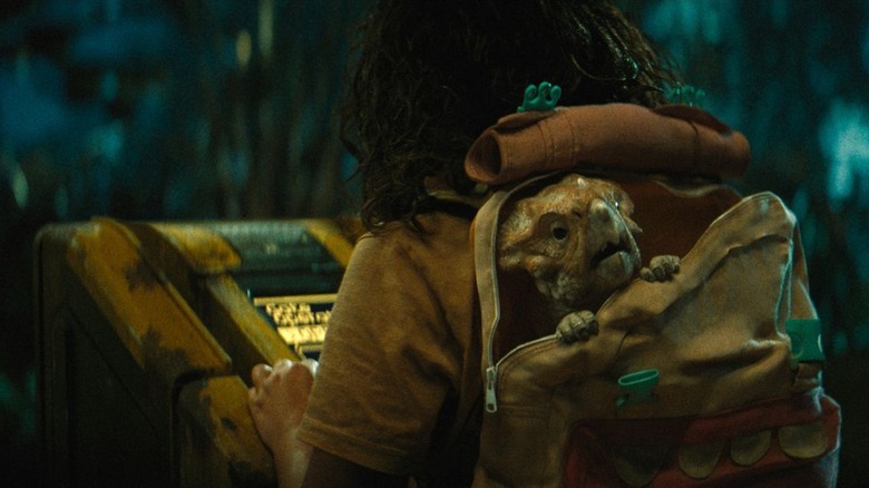 A terrified Dolores pokes out from a backpack in "Jurassic World Rebirth" (2025)