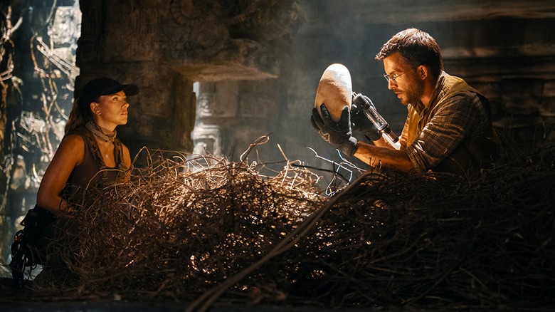 Dr. Henry Loomis inspecting dinosaur egg while Zora Bennett watches