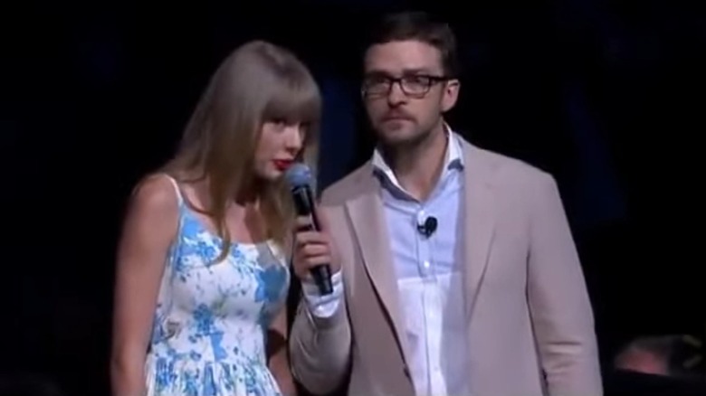 Justin Timberlake in glasses holding a microphone up to Taylor Swift