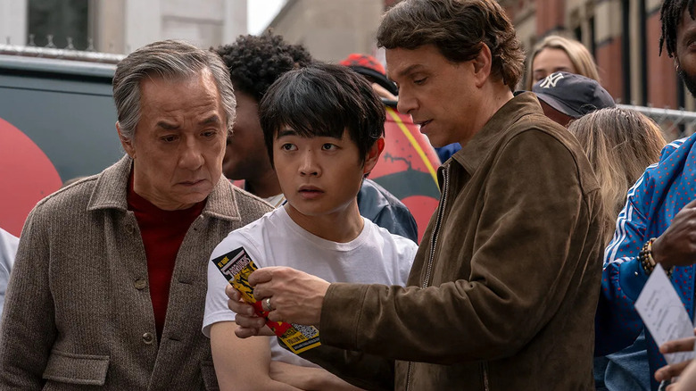Mr. Han and Daniel LaRusso looking at a pamphlet with Li Fong