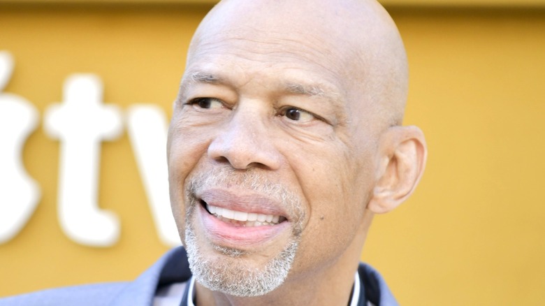 Abdul-Jabbar smiling by yellow background