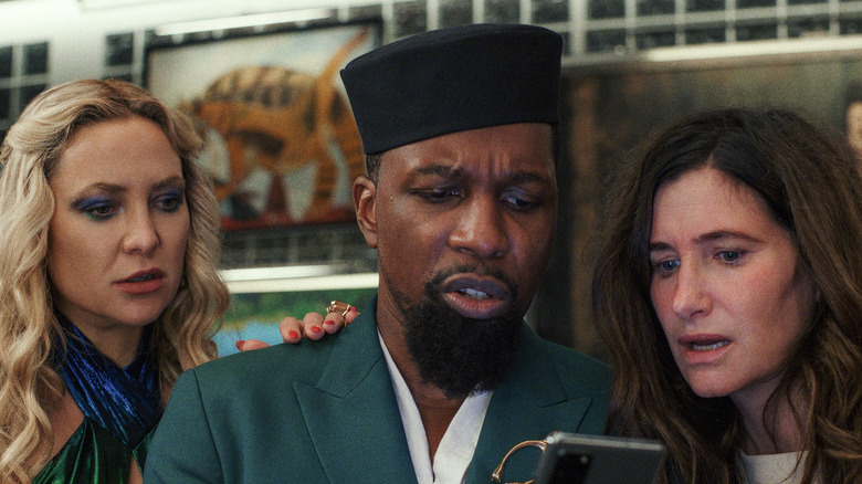 Kate Hudson, Leslie Odom Jr., and Kathryn Hahn looking at phone in Glass Onion