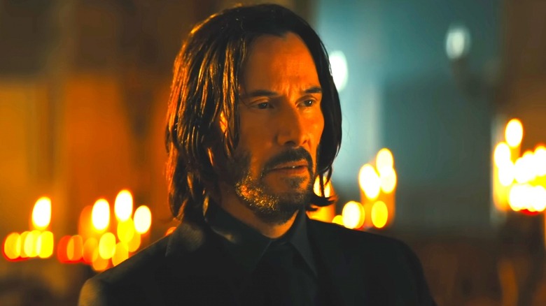John Wick stands in front of candles