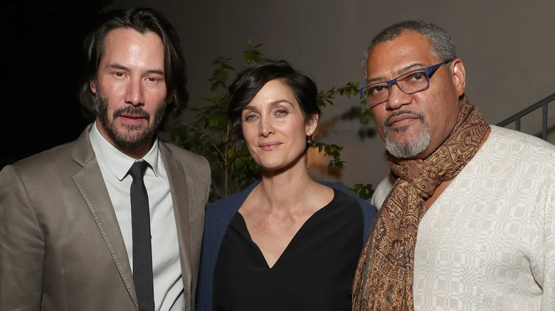 Keanu Reeves, Carrie-Anne Moss, and Laurence Fishburne posing at after party for the premiere of 