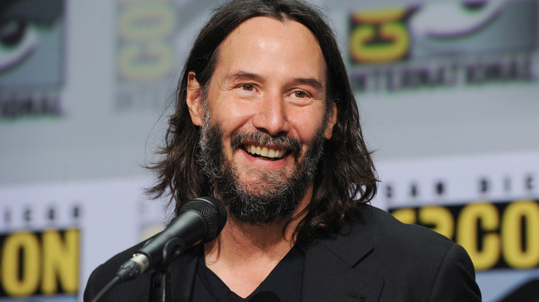 Keanu Reeves smiling near microphone