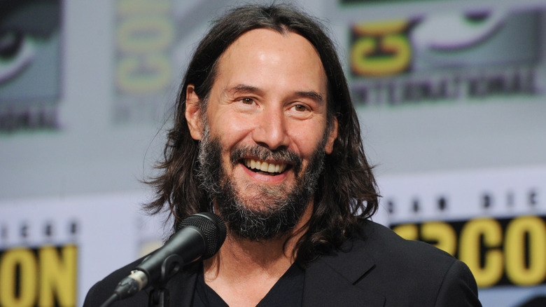 Keanu Reeves smiling near microphone