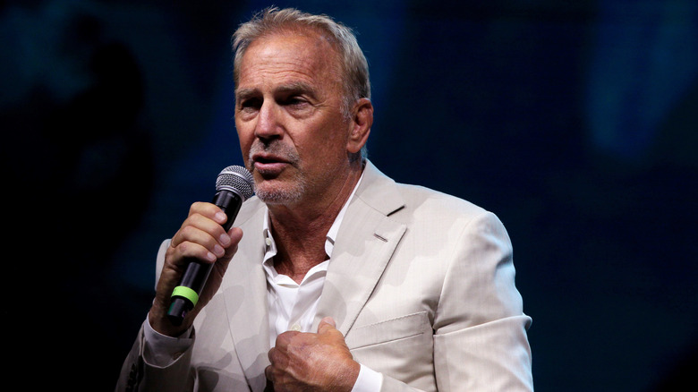 Kevin Costner talks into a mic on stage