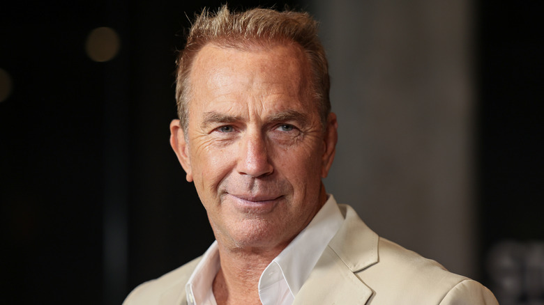 Kevin Costner smiling in a beige suit