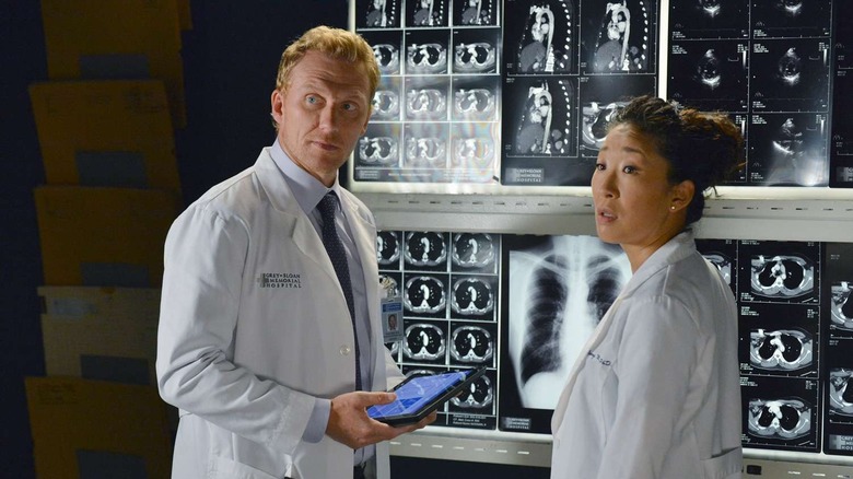 Owen and Cristina with X-rays behind them looking surprised on Grey's Anatomy