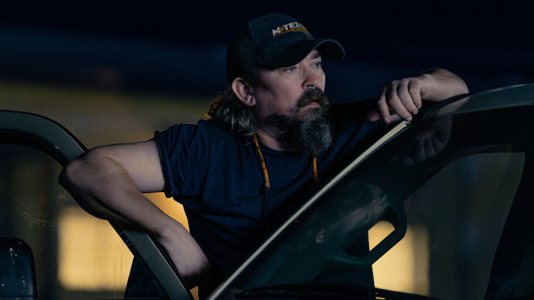 Dale leaning on the open door of a car in "Landman"