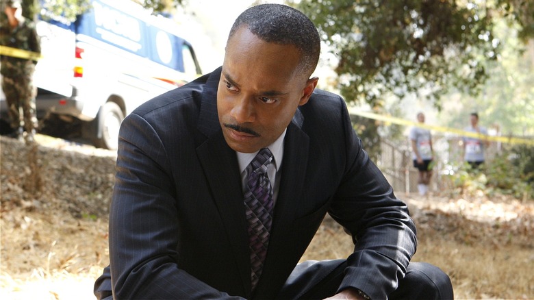 Leon Vance leaning down by crime scene in 