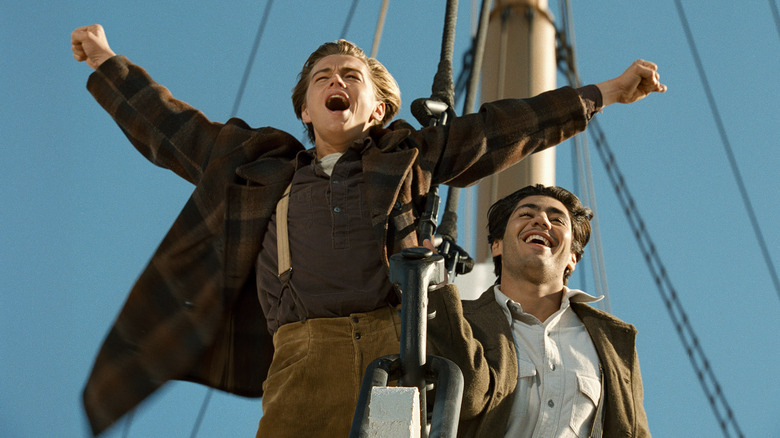 Jack throws his arms in the air with Fabrizio behind him in Titanic (1997)