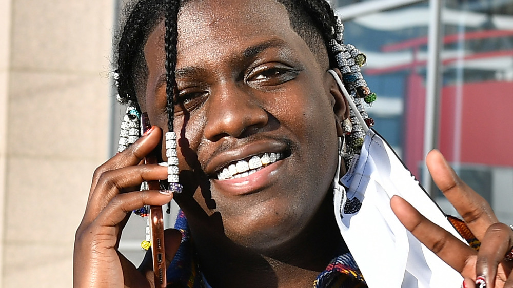 Lil Yachty talks on a cell phone and gives a peace sign