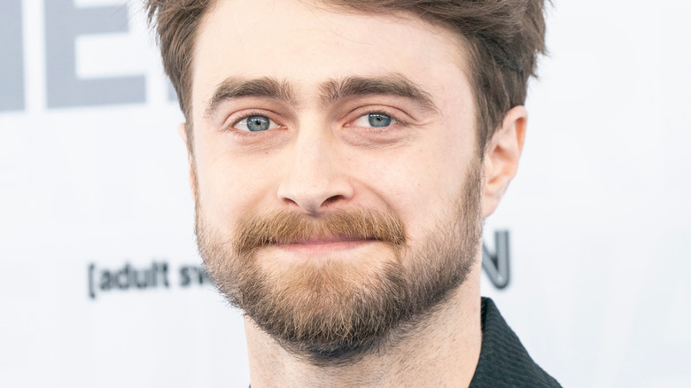 Daniel Radcliffe smiling against a white backdrop