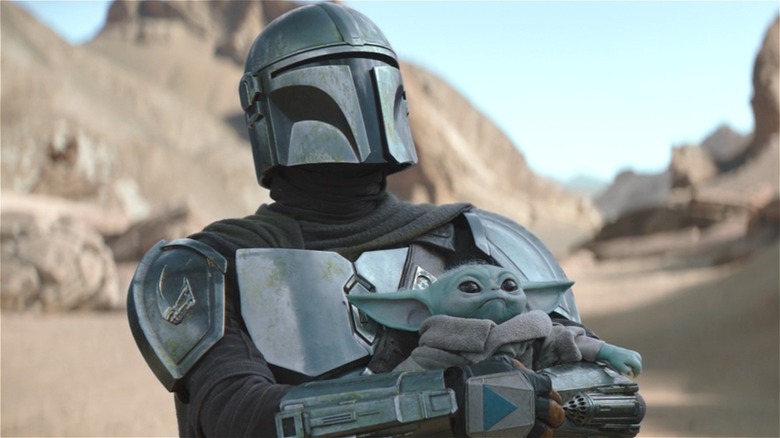 The Mandalorian holding Grogu