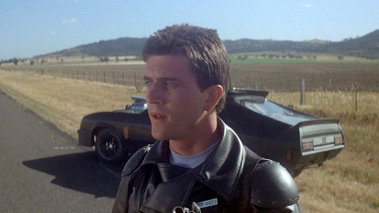 Officer Max in front of his car on the side of the road in "Mad Max" (1979)